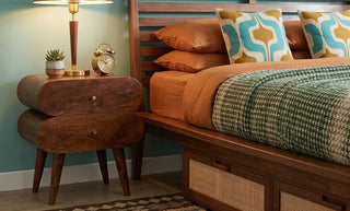 Mid century modern wooden nightstand next to a bed in a stylish bedroom interior