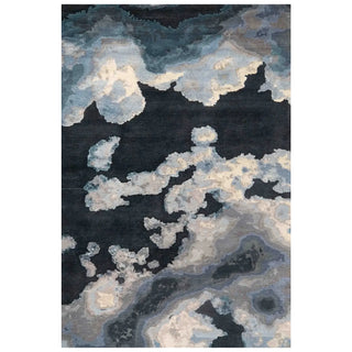 An abstract area rug featuring a textured, cloud-like pattern in shades of navy blue, charcoal gray, slate gray, and off-white.