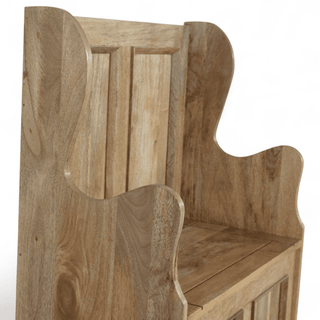 Rear three-quarter view of a mango wood monk's bench showing the high panelled back and curved wing side