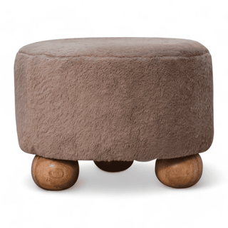 Front view of a round brown faux fur footstool with wooden ball legs, showcasing its plush design.