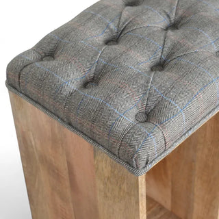 Close-up of the buttoned grey tweed cushioned top and mango wood corner of a shoe storage bench