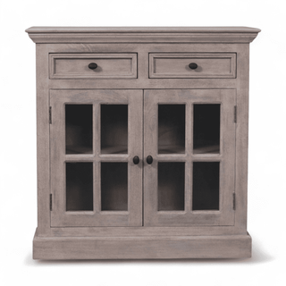 Front view of a rustic light grey cabinet featuring two drawers, two glazed doors, and black knobs for a classic look.