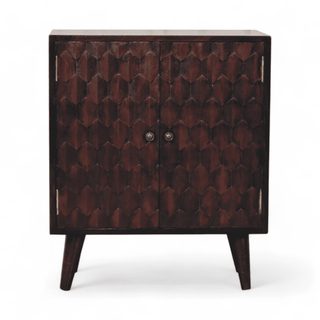 Front view of a dark wooden cabinet with intricate hexagonal carvings and two round metal knobs.