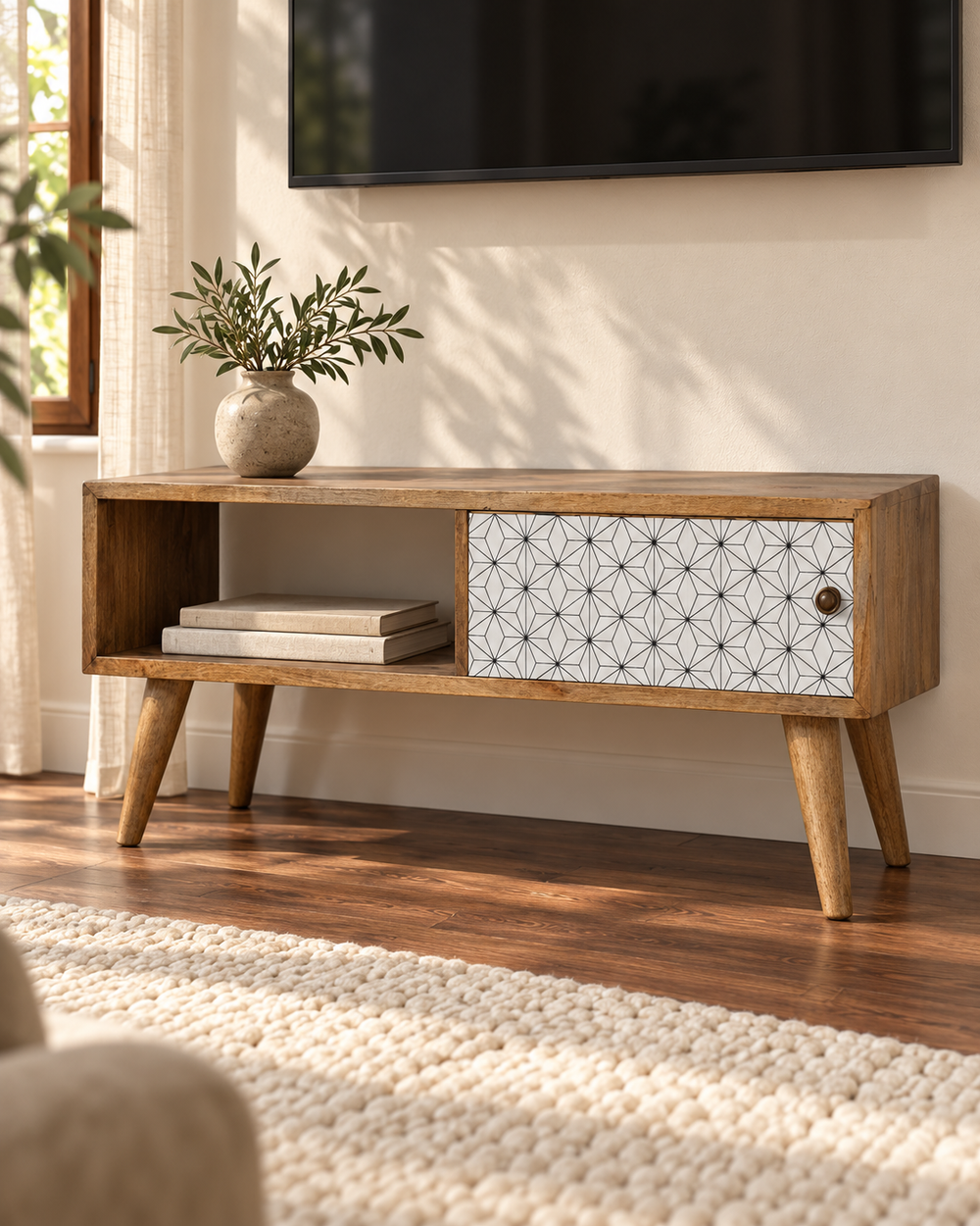 Mid-century wooden media unit with open shelving, a patterned cabinet door and tapered legs beneath a wall-mounted television.
