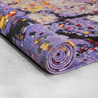 Rolled Bloomscape wool and silk rug showcasing its detailed hand-knotted pile and colourful abstract pattern