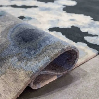 Corner of a dark navy wool rug curled over to show the hand-knotted back