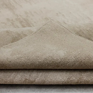 Folded corner of a soft greige wool rug showing its low, velvety pile