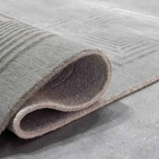 Corner of a grey wool and silk rug curled back to show the hand-knotted underside