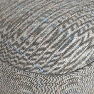 Close-up of a herringbone patterned fabric in gray and beige with thin light blue windowpane lines.