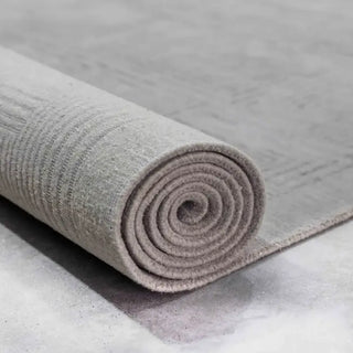 Rolled hand-knotted grey rug showing its dense, even pile
