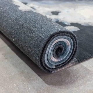 Rolled hand-knotted wool rug showing its layered blue and grey pile