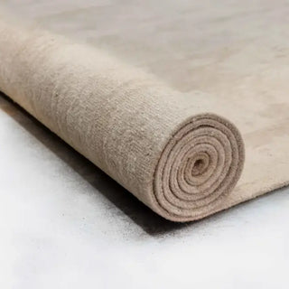 Tightly rolled sand colored hand-knotted rug showing its dense layered pile